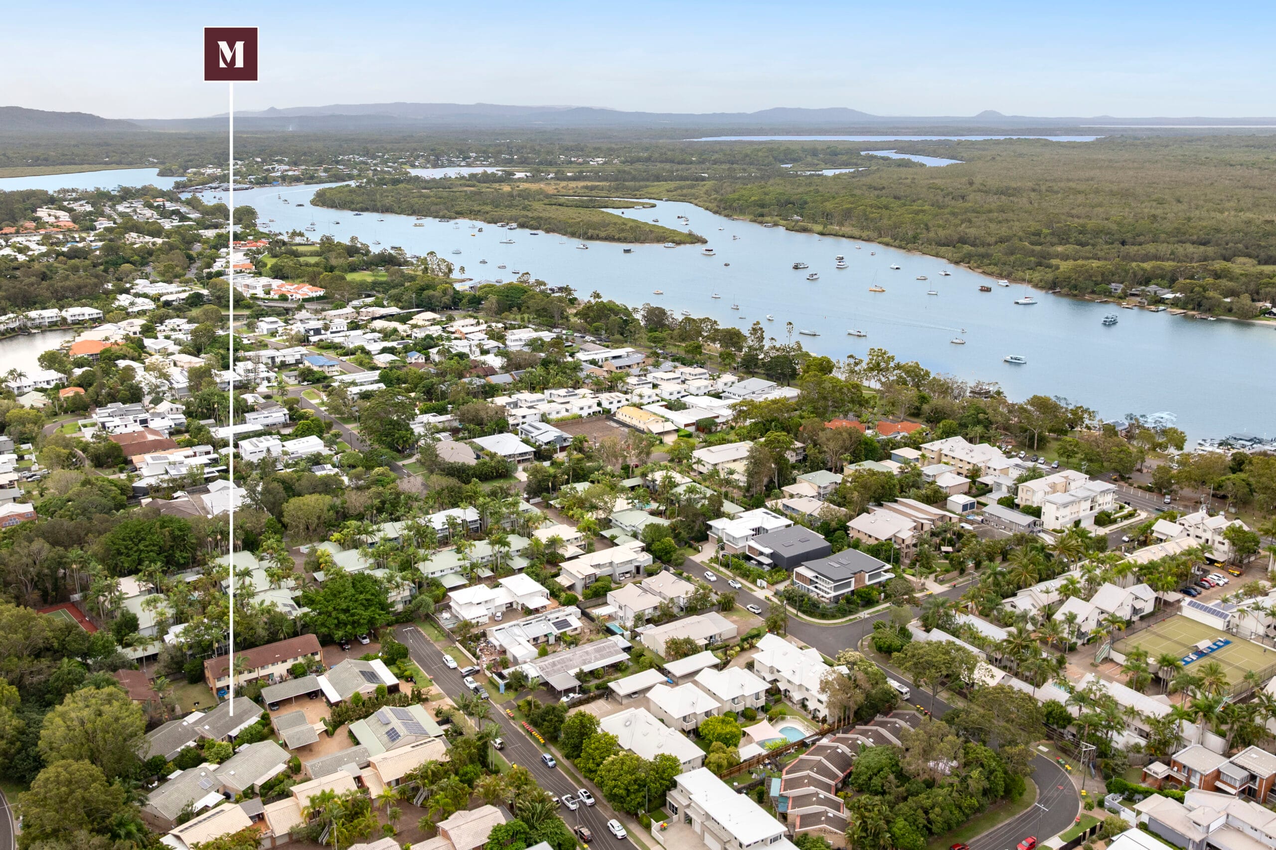The Noosa River winding through Noosaville with low-rise homes and bushland.